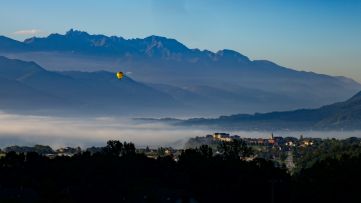 Vue d'une Montgolfière au dessus du village des Marches le matin dans la brume, le massif de Belledone enneigée en arrière plan